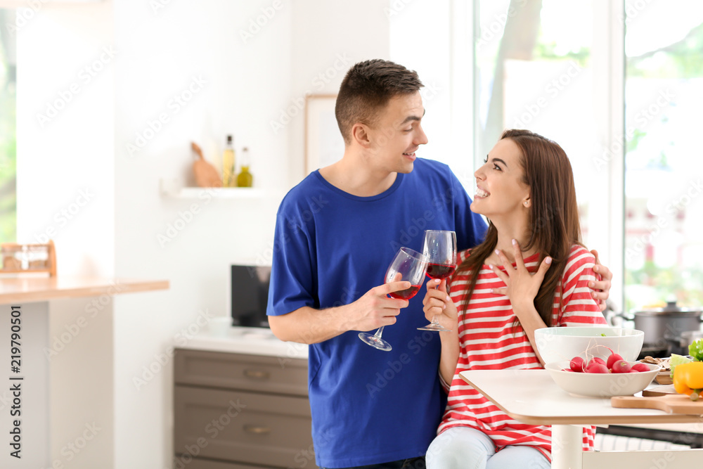 Young couple drinking wine while cooking together in kitchen Young couple drinking wine while cooking together in kitchen