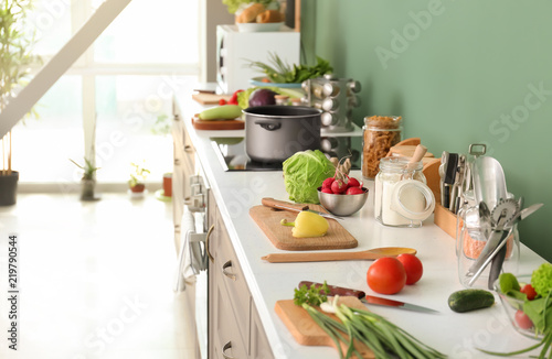 Cooking utensils with fresh vegetables on table in modern kitchen