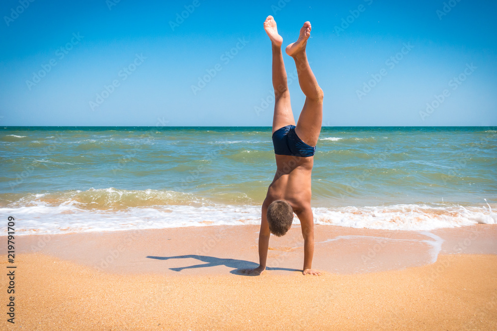 Boy standing upside down on the beach Boy standing upside down on the beach
