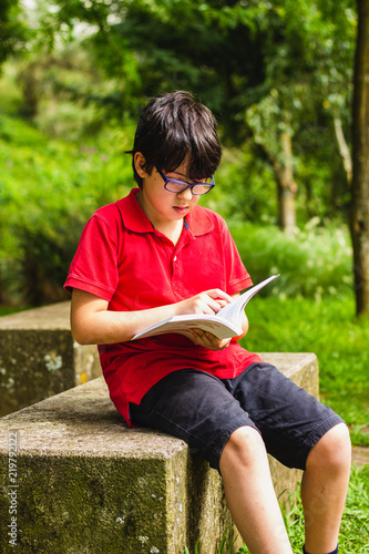 Cute boy, reading a book in the park