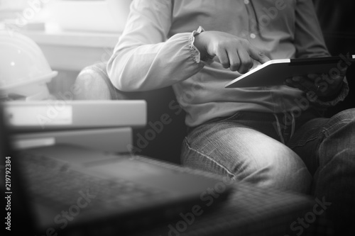 Businesswoman in casual dress holding tablet with online while making orders. Black and white picture.