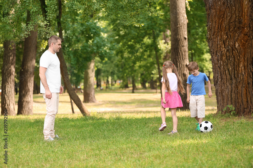 Happy family playing football in park on summer day Happy family playing football in park on summer day