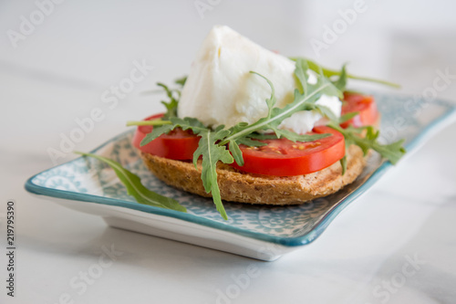 Italian style toast with light bread, arugula, tomato and mozzarella cheese 