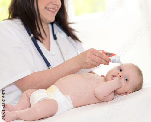 Doctor pediatrician measuring temperature of baby