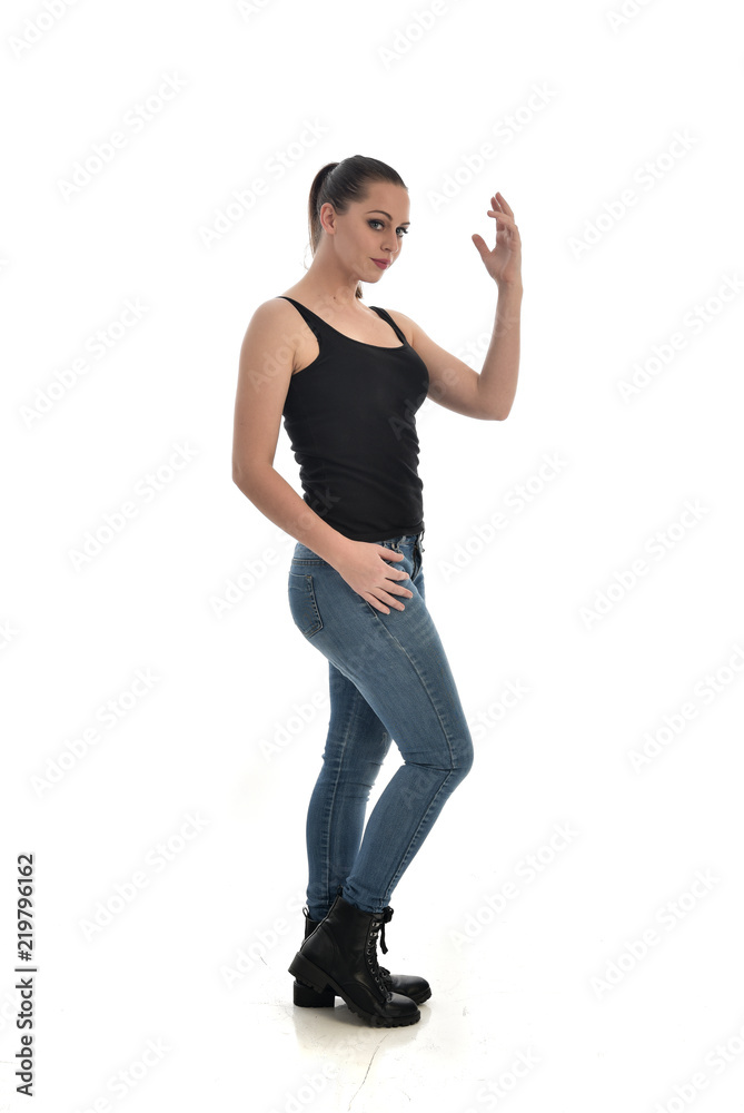 full length portrait of brunette girl wearing black single and jeans. standing pose in side profile. isolated on white studio background. full length portrait of brunette girl wearing black single and jeans. standing pose in side profile. isolated on white studio background.