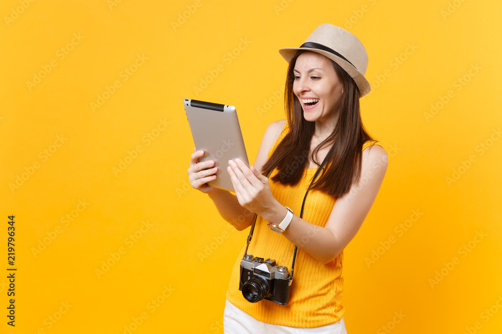 Traveler tourist woman in summer casual clothes, hat holding tablet pc computer isolated on yellow orange background. Girl traveling abroad to travel on weekends getaway. Air flight journey concept.
