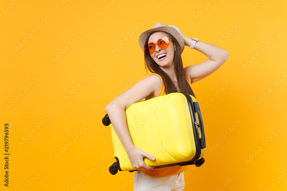 Traveler tourist woman in summer casual clothes, hat with suitcase isolated on yellow orange background. Female passenger traveling abroad to travel on weekends getaway. Air flight journey concept. - obrazy, fototapety, plakaty 