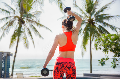 Asian sportgirl exercise with dumbell or weightlifting workout. Sports and fitness concept. photo