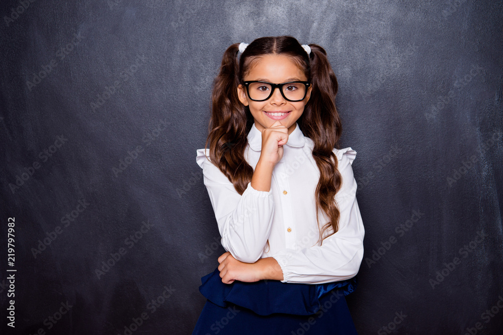 Φωτογραφία Portrait of positive glad nice adorable cute small little girl with curly ponytails in white formal blouse shirt, skirt, touching chin