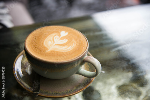 White cup of coffee latte art leave from fresh milk on the table.