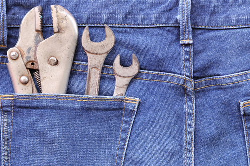 Blue jeans of back pocket and have old wrench tool with rust.