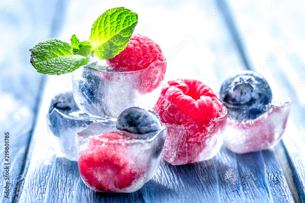fresh berries with mint in ice cubes on wooden background - obrazy, fototapety, plakaty 