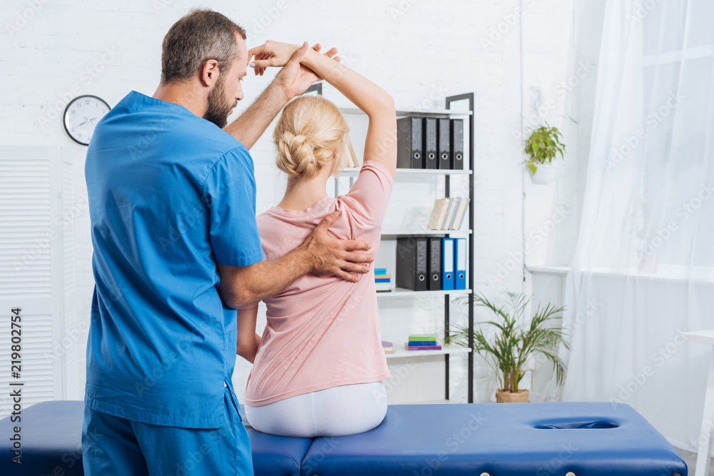 Fototapeta premium physiotherapist stretching patients arm on massage table in hospital