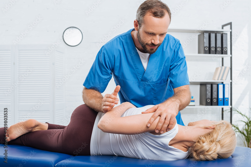 Obraz premium partial view of physiotherapist stretching patient on massage table in hospital