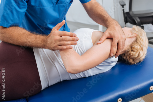 cropped shot of physiotherapist stretching patient on massage table in hospital
