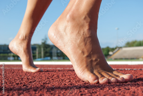 Bare feet from the front at the time of departure on the athletics track seen from the front