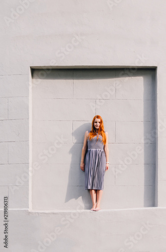 Young redhead woman over a grey background