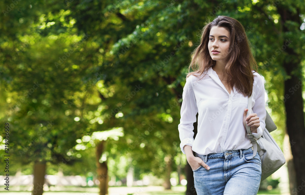 Casual woman walking alone through green park Casual woman walking alone through green park
