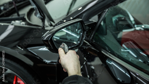 Worker applying paint protection film on black car