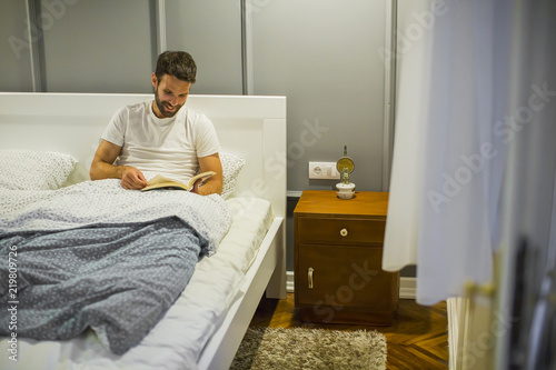 Young man reading book in bed