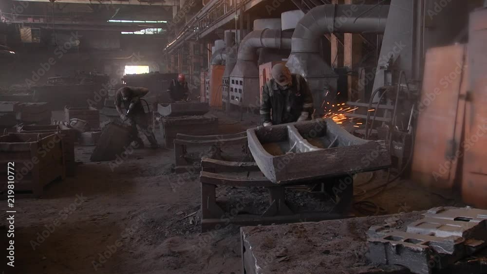 Cleaning of the molding mixture. Roughing of a metal product. The worker clears the tubing ring with an angular grinder. Cleaning of the molding mixture. Roughing of a metal product. The worker clears the tubing ring with an angular grinder.