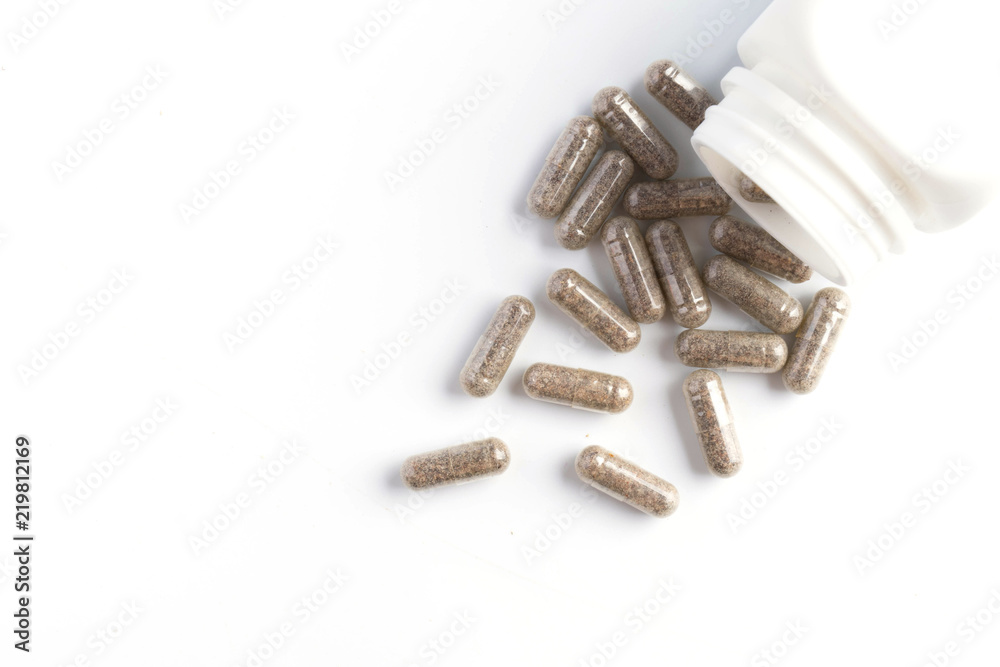 herb capsules spilling out of a bottle isolated