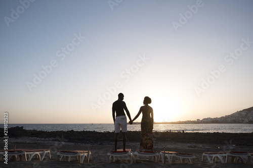 happy couple in love black skin have fun and happiness in front of a wanderful sunset over the sea. love and together life forever concept for two man and woman in relationship on vacation photo