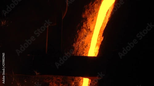 Room for the manufacture of metal products by casting. Casting shop for gasified models. The molten metal is poured from the induction furnace into the ladle. Sparks of hot metal fly apart. Close-up. photo