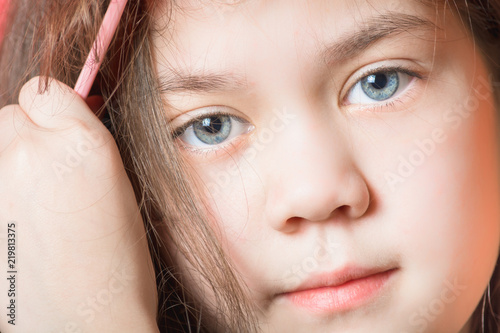 Beautiful girl combs her hair looking up on a red background