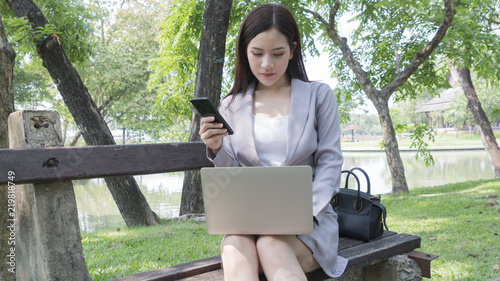 business woman use computerand smartphone and think in the garden park photo