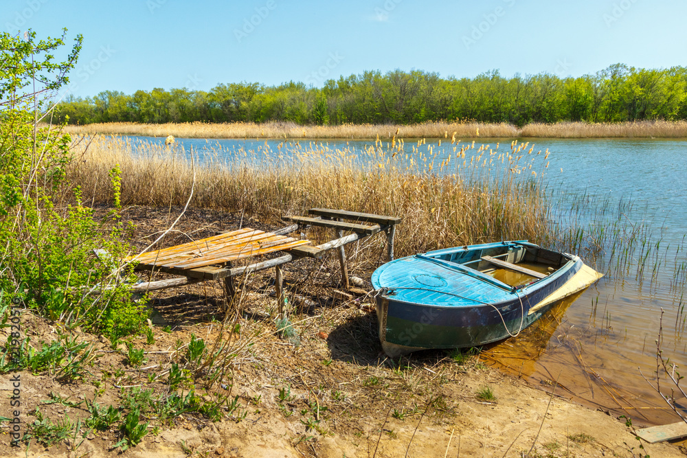 The empty fishing metal boat on the riverbank