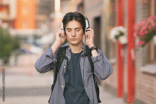 A man in headphones listens to music. Fresh air. Street © Alena