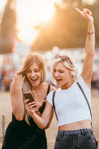 Young female friends having fun and using mobile phone photo