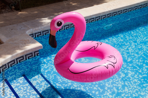 Flamingo hinchable de color rosa dentro de una piscina. Vista superior photo