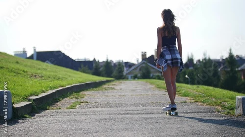Wallpaper Mural Young girl riding on an empty path on a skateboard, rear view Torontodigital.ca