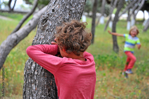 Two kids playing hide and seek in park
