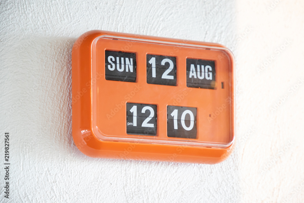 orange flip clock on white wall, retro analog timer. show time on 12 august  at lunch time. foto de Stock | Adobe Stock