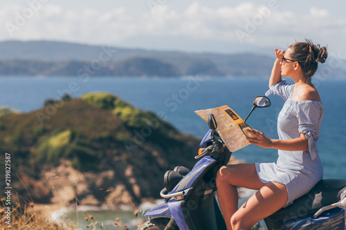 Woman in summer dress on motorbike holding map searching right path 