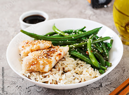 Fish fillet served with rice, soy sauce and green beans in white plate. Asian food.