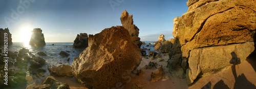 Panoramic view of the first sunlight on the rocky coastline of the Algarve, Portugal during upcoming tide