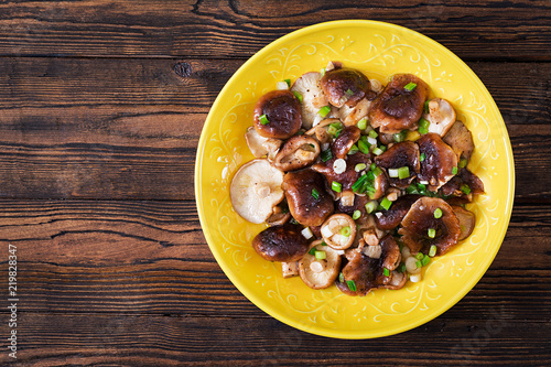 Fried mushrooms shiitake with green onion on wooden background. Chinese food.Top view. Flat lay