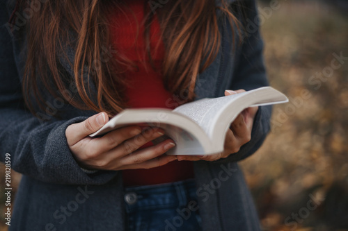 Woman in warm clothes holding opened book on the front of picture Outdoor Autumn photo