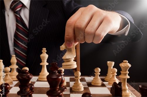 Businessman Hand Holding a Chess Piece on a Chessboard