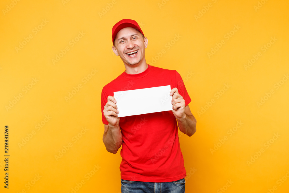 Delivery man in red uniform isolated on yellow orange background. Professional male employee courier in cap, t-shirt hold white empty blank paper. Service concept. Copy space place for text or image.