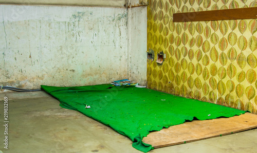 Indoor view of a room inside of a refuge center with a green blanket in the ground, from people that escape from their country Venezuela