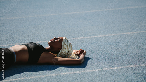 Female sprinter lying on running track after workout