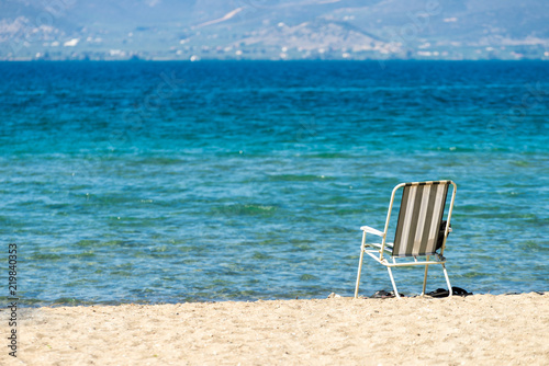 Deck chair on sand beach next to water © Voyagerix