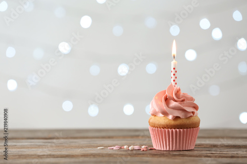 Canvas Print Delicious birthday cupcake with burning candle and space for text on blurred lig