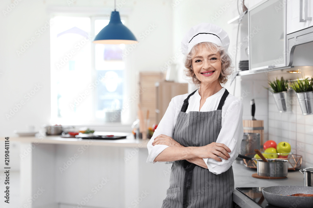 Professional female chef standing near table in kitchen Professional female chef standing near table in kitchen