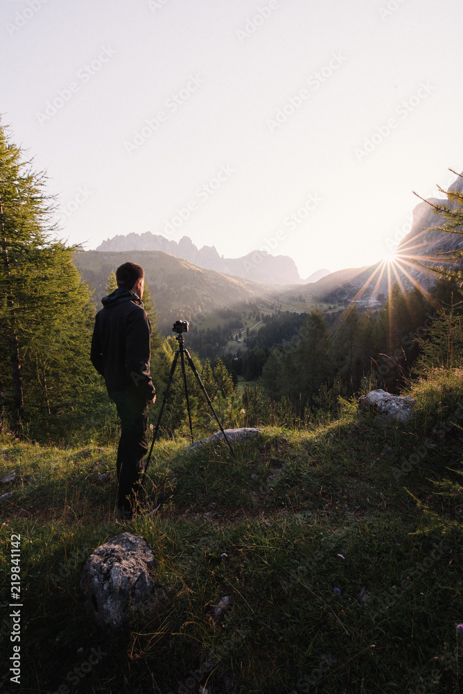 Photographer taking a photo of a sunrise with a tripod.